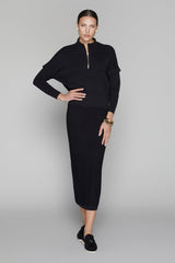 Woman wearing a black outfit with a high-low hem on a gray background