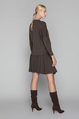 Woman wearing a brown dress and high boots on a gray background