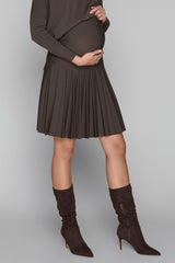 Person wearing a brown pleated skirt and matching knee-high boots on a plain background