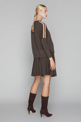 Woman wearing a brown dress and matching knee-high boots on a gray background