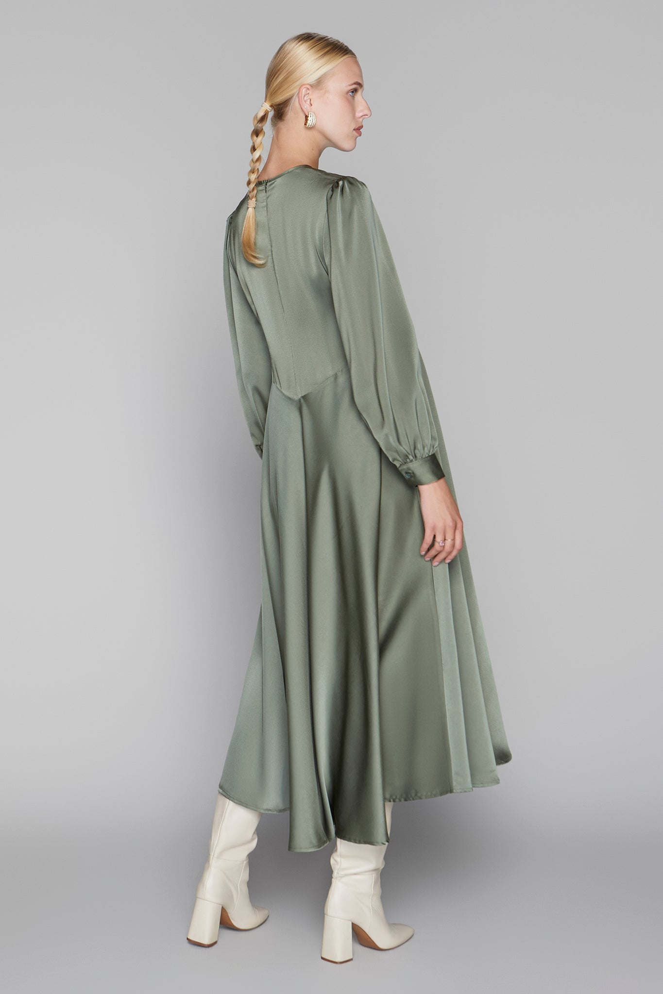 Woman wearing a green dress with long sleeves and a plain background