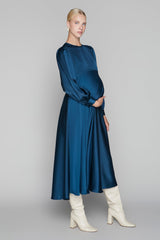 Woman wearing a blue dress and white boots on a gray background