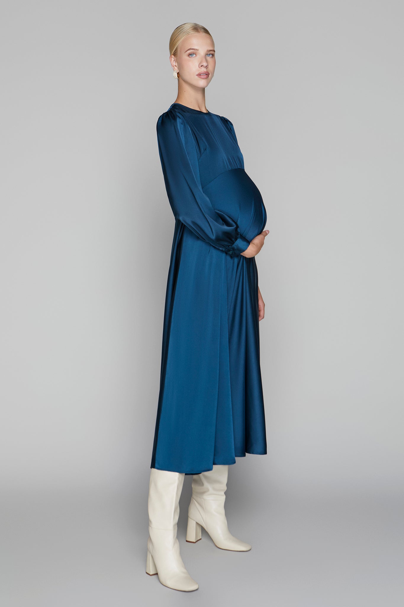 Woman wearing a blue dress and white boots on a gray background