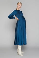 Woman wearing a blue dress with long sleeves and white boots on a gray background