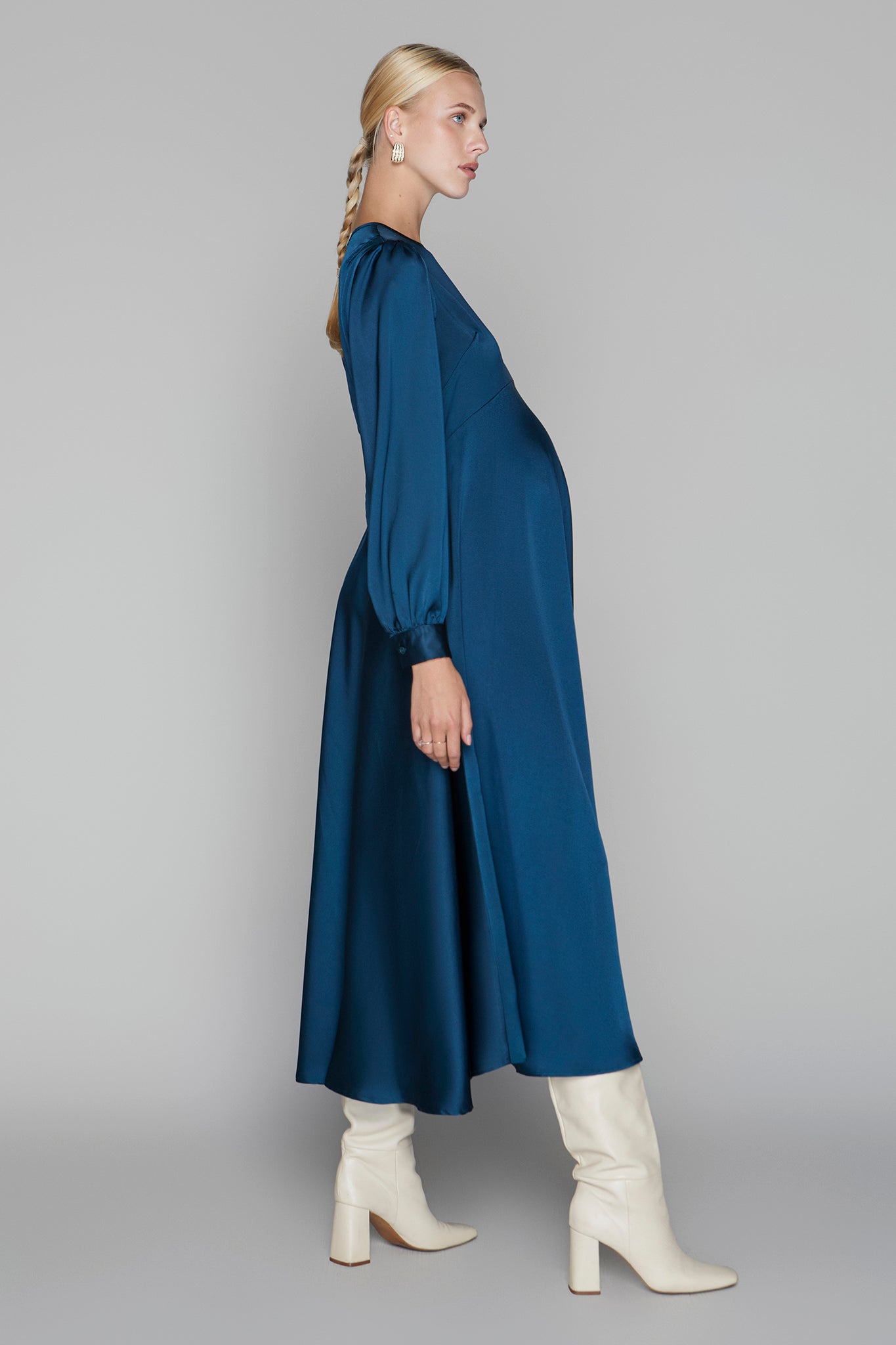 Woman wearing a blue dress and white boots on a gray background