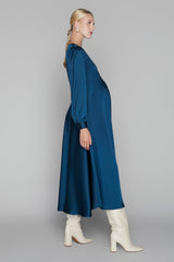 Woman wearing a blue dress and white boots on a gray background