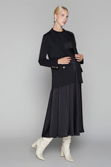 Woman wearing a black outfit with a jacket and skirt on a gray background