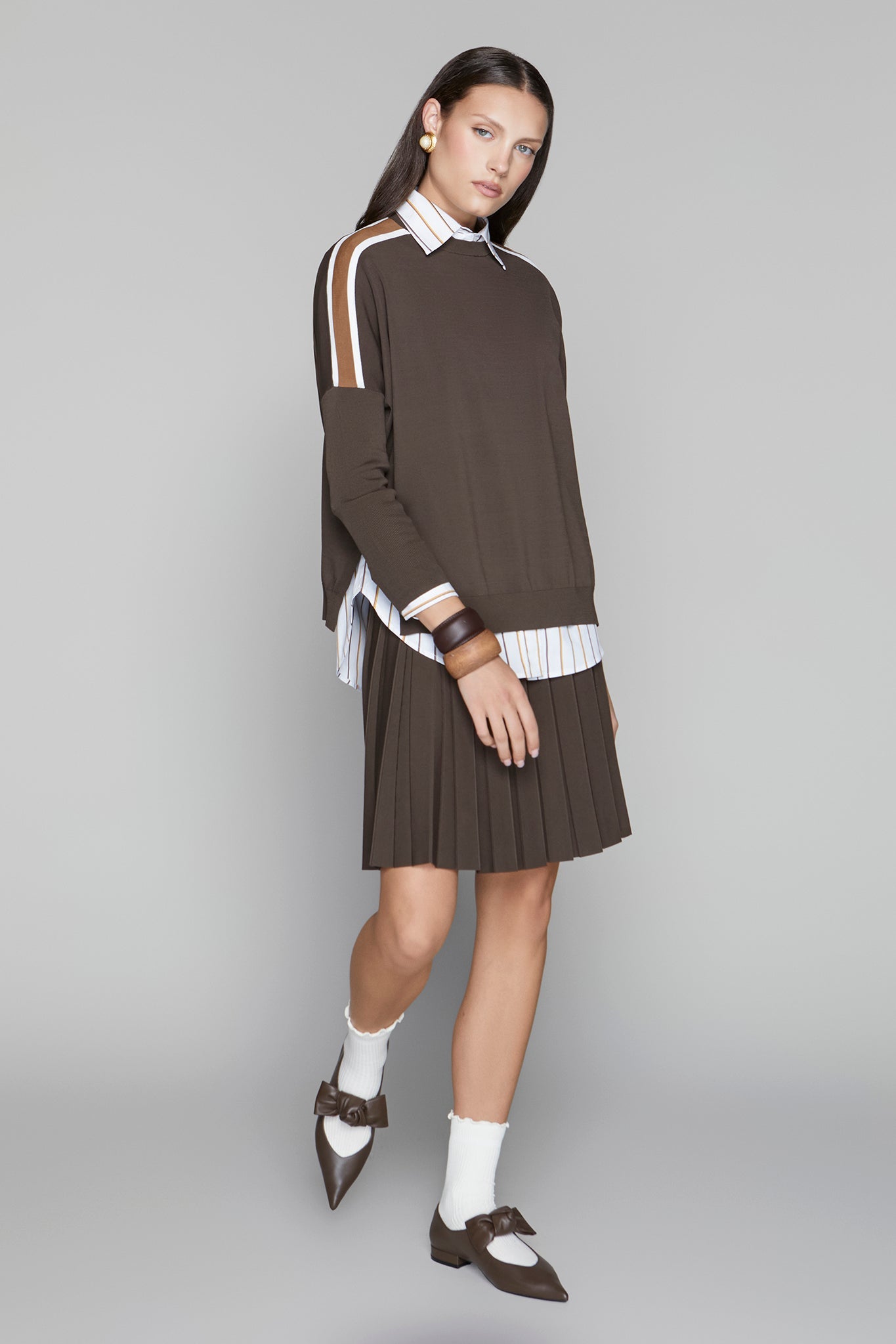 Woman wearing a brown dress with white accents on a gray background