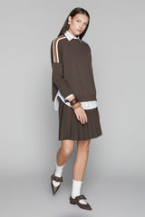 Woman wearing a brown dress with white accents on a gray background