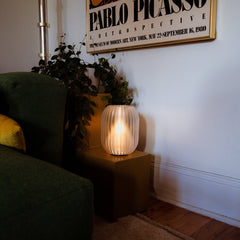 Living room with a green sofa, plant, and lit candle on a small table below a Pablo Picasso poster.