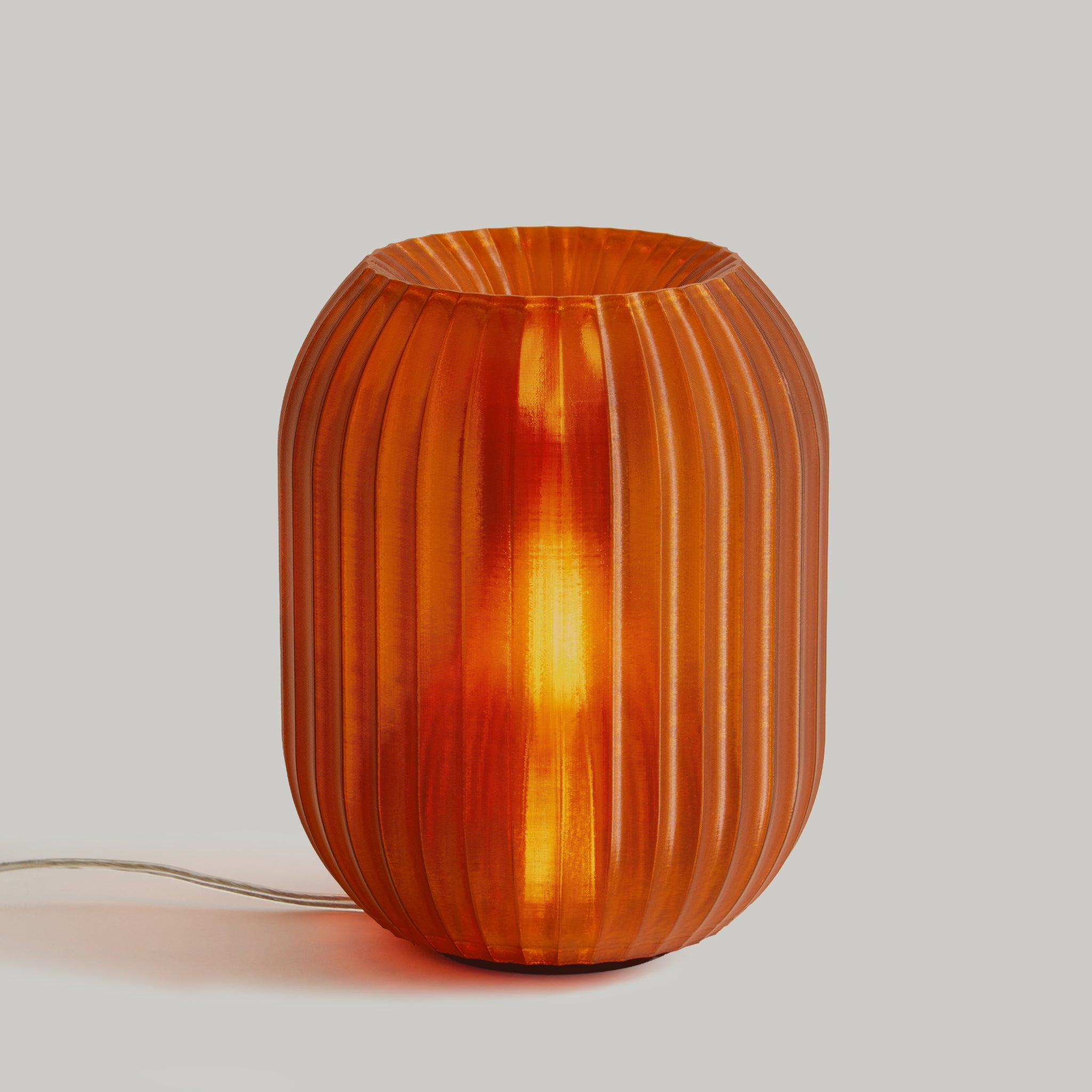 Orange ribbed glass table lamp on a light gray background