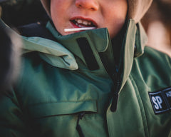 Person wearing a green jacket with a hood, partially obscuring their face.