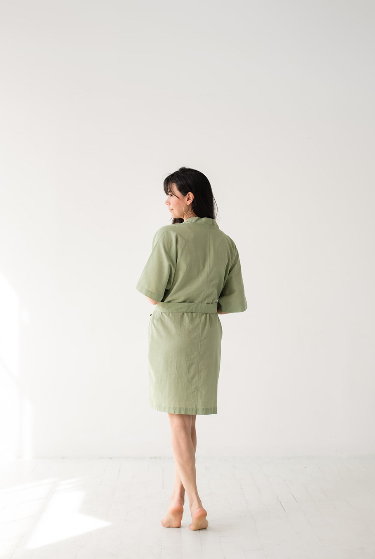 Woman wearing a green robe standing against a white background