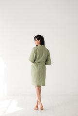 Woman wearing a green robe standing against a white background