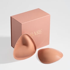 Bare bra pads with a matching pink box on a light gray background