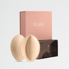Two beige circular products in front of a pink 'BARE' box on a light gray background