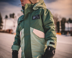 Person wearing a green jacket with a brand logo in an outdoor setting