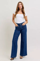 Woman wearing a white top and blue jeans on a plain background