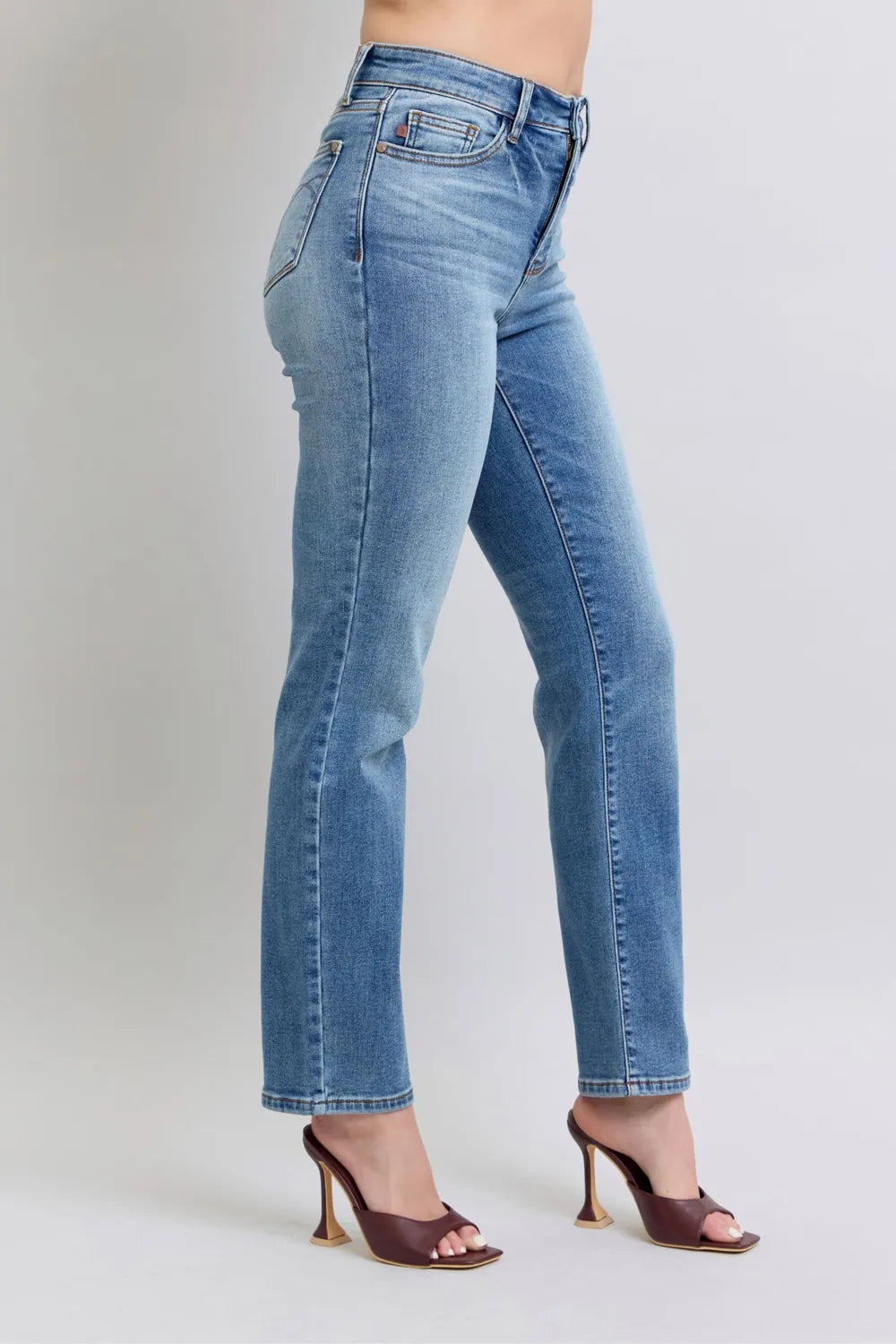 Blue jeans worn by a person on a plain background