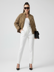 Woman wearing a green jacket, white pants, and black shoes on a white background