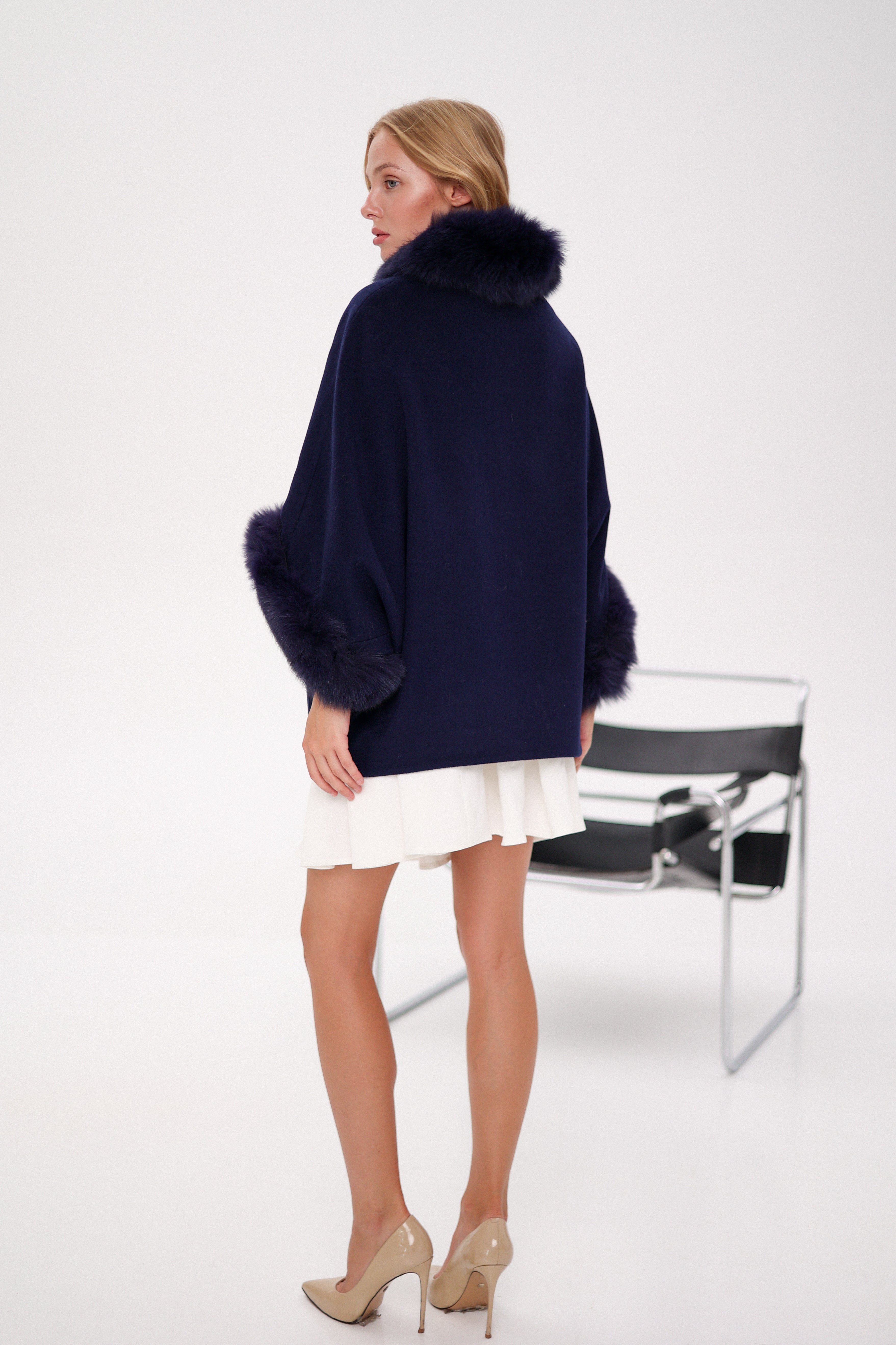 Woman wearing a navy blue sweater with fur trim on a white background