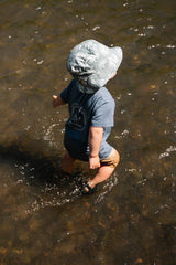 Child wearing a rain hat walking in shallow water