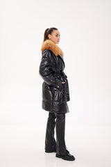 Person wearing a black puffer coat with fur trim on a white background
