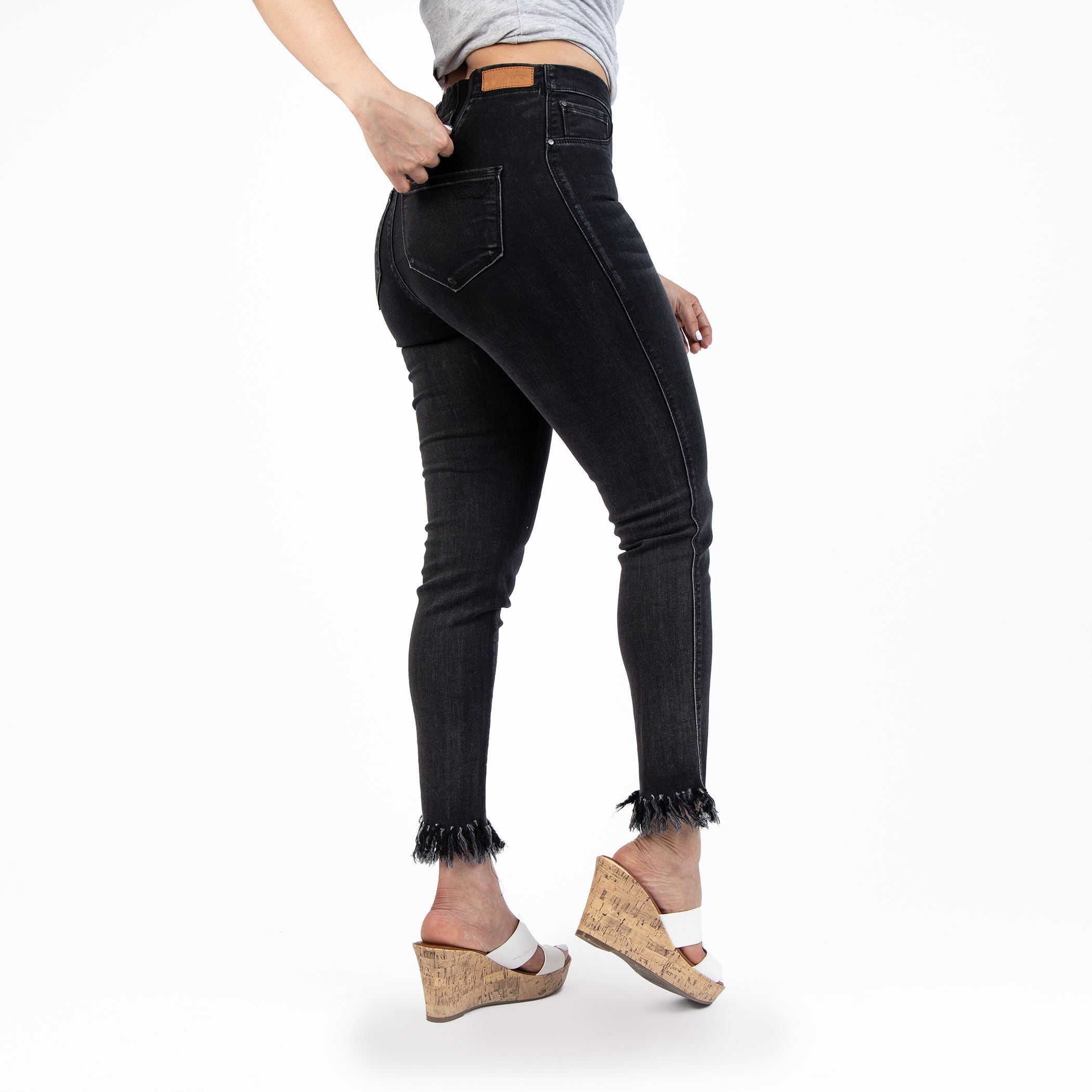 Person wearing black jeans with frayed hems on a white background