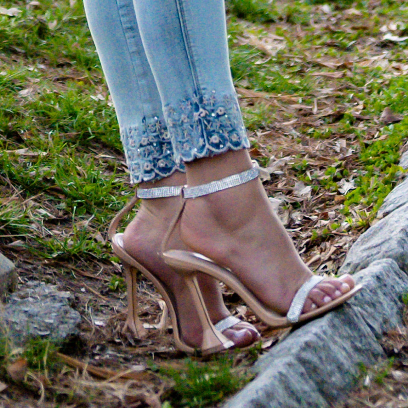 Close-up of feet wearing high-heeled sandals with a blurred natural background