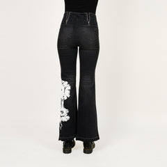 Black flared jeans with white floral design on a white background