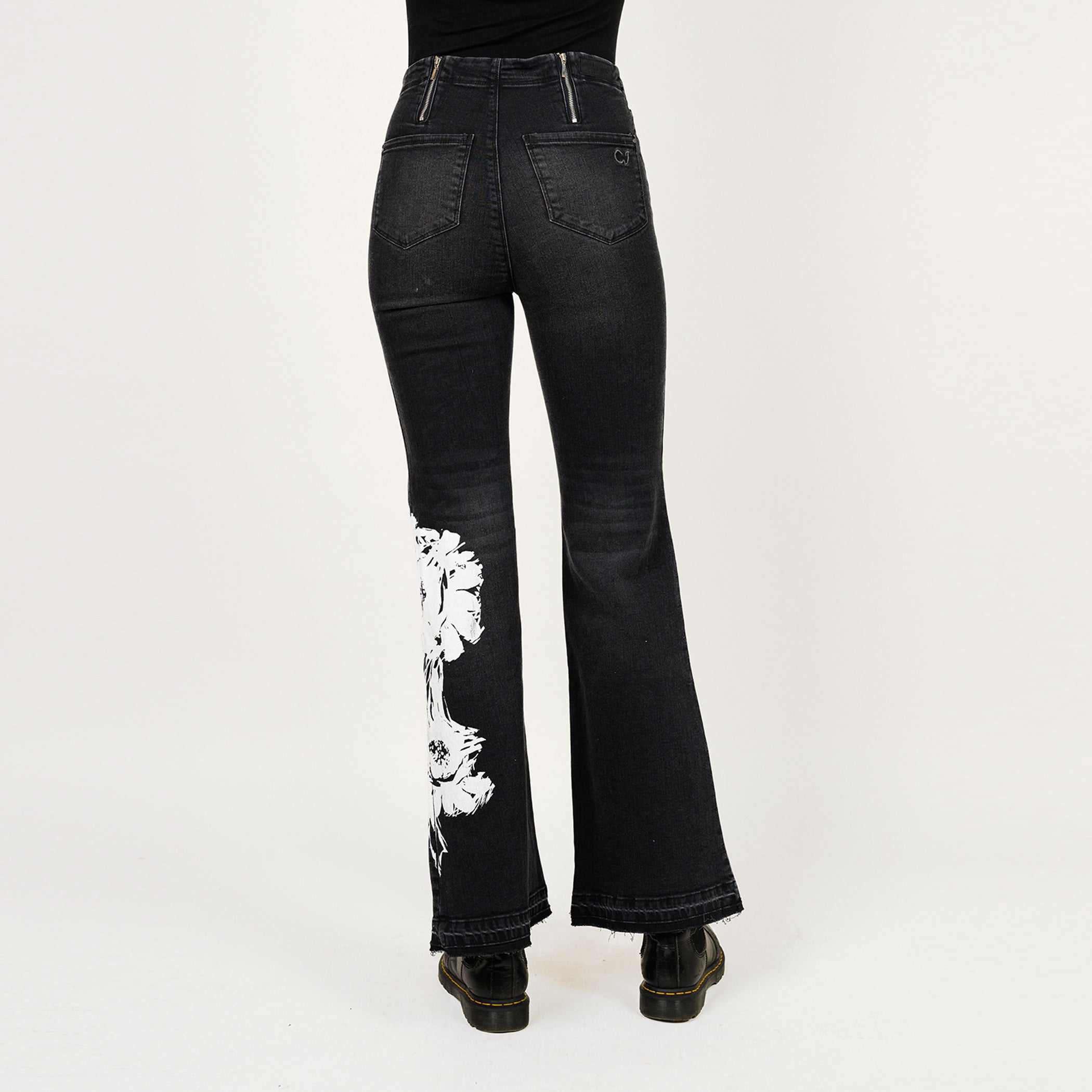 Black flared jeans with white floral embroidery on a white background