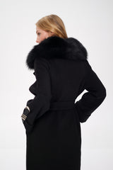 Woman wearing a black coat with a fur-lined hood on a white background