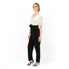 Woman wearing a white lace top and black pants on a white background