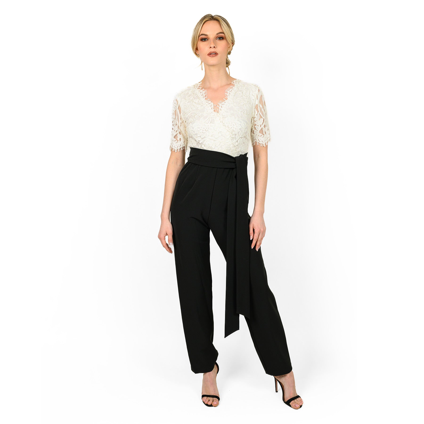 Woman wearing a white lace top and black high-waisted pants on a white background