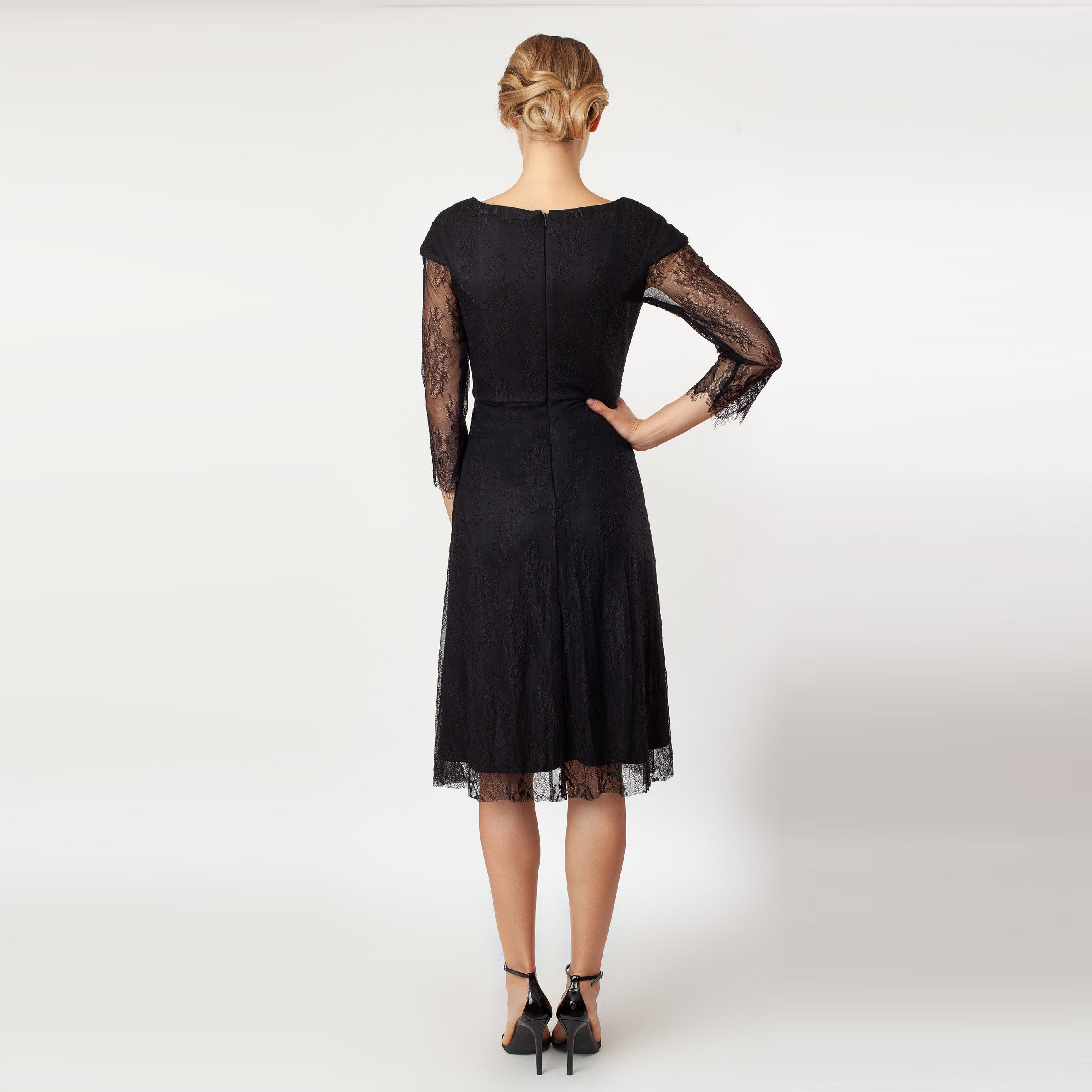 Black dress with sheer sleeves worn by a model on a white background