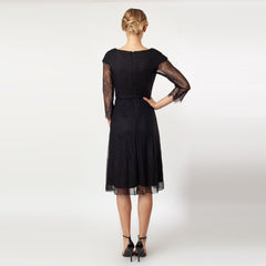 Black dress with sheer sleeves worn by a model on a white background