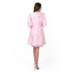 Woman wearing a pink and white patterned dress on a white background