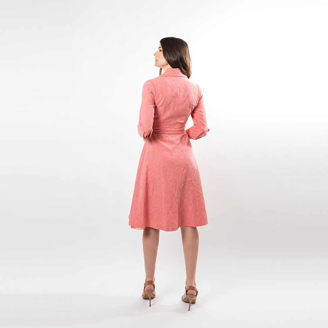 Woman wearing a pink dress standing against a white background