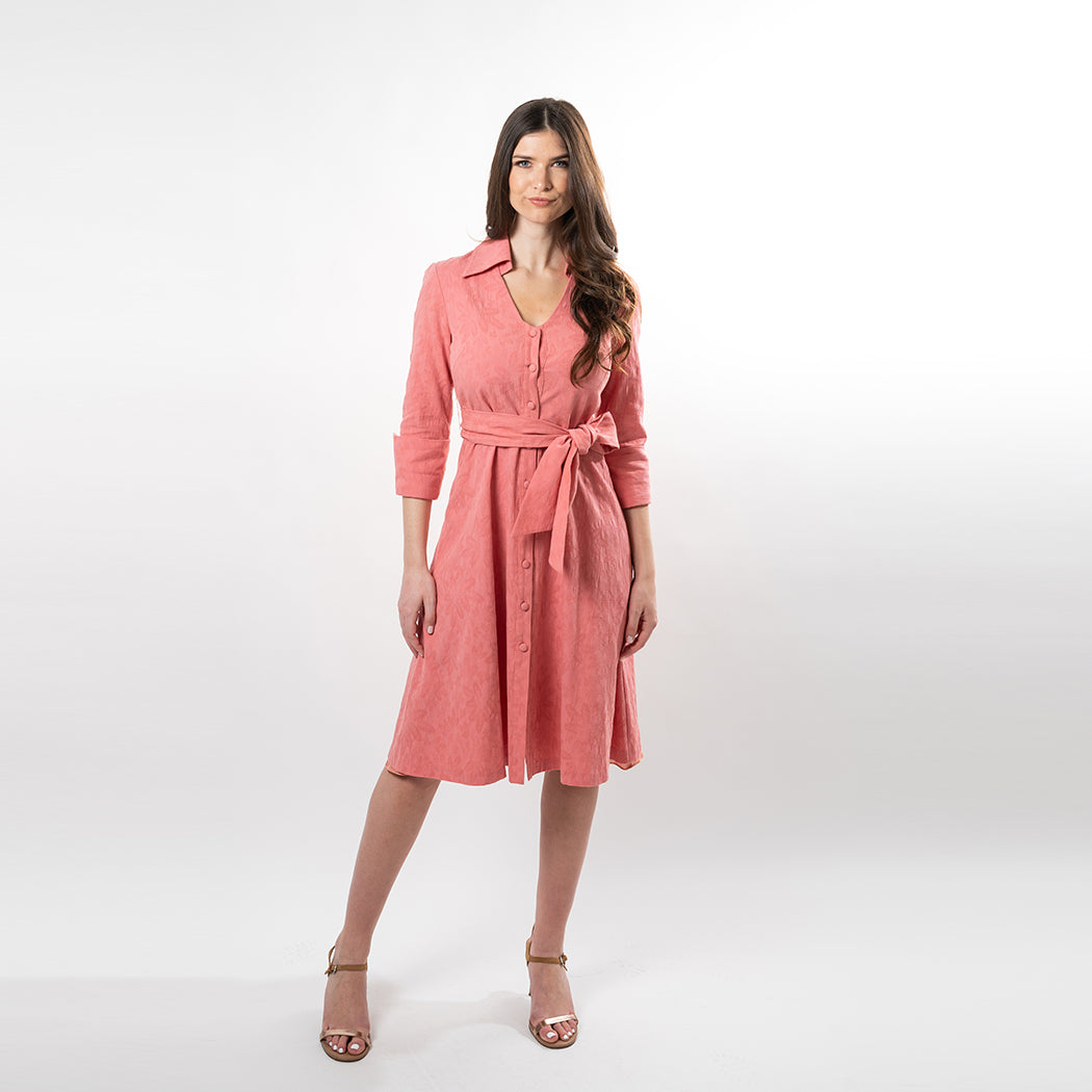 Woman wearing a pink dress with a belt on a white background