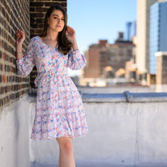 Woman in a floral dress standing on a rooftop with cityscape in the background