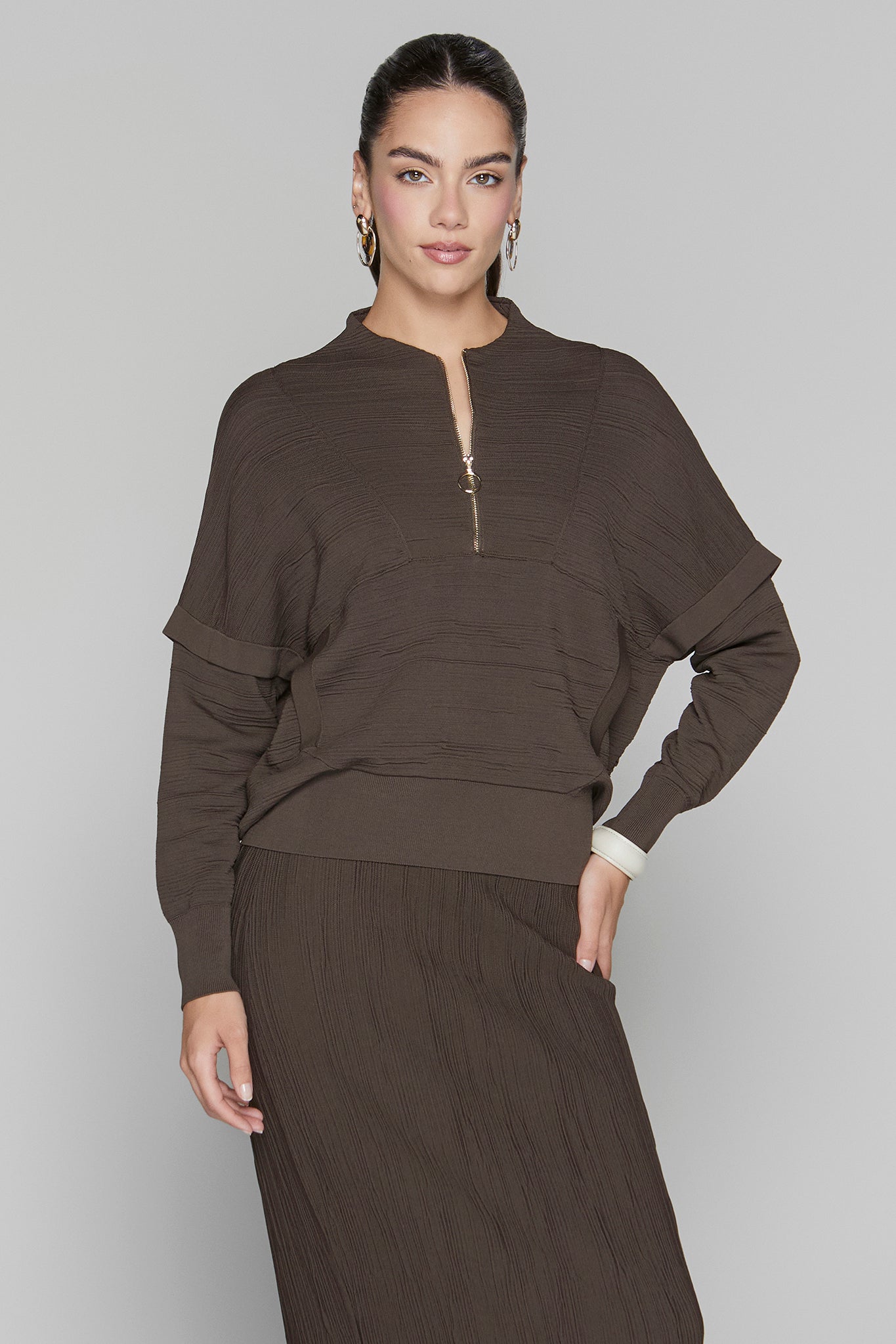 Woman wearing a brown outfit against a plain background