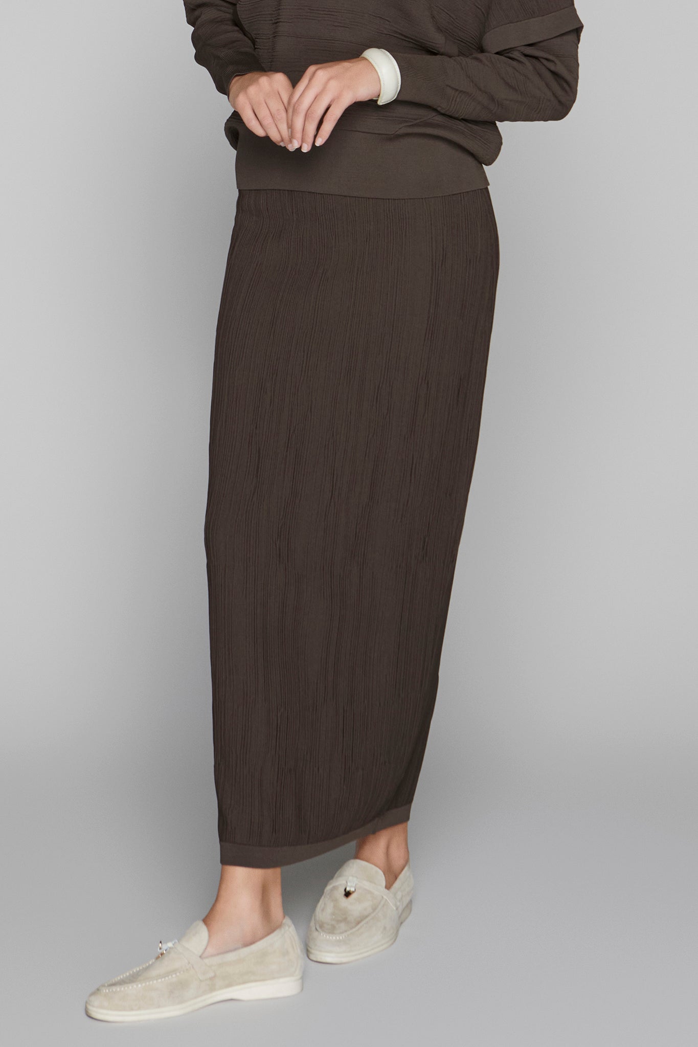Person wearing a brown skirt and sweater on a plain background