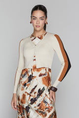 Woman wearing a patterned dress with a cardigan over it on a plain background