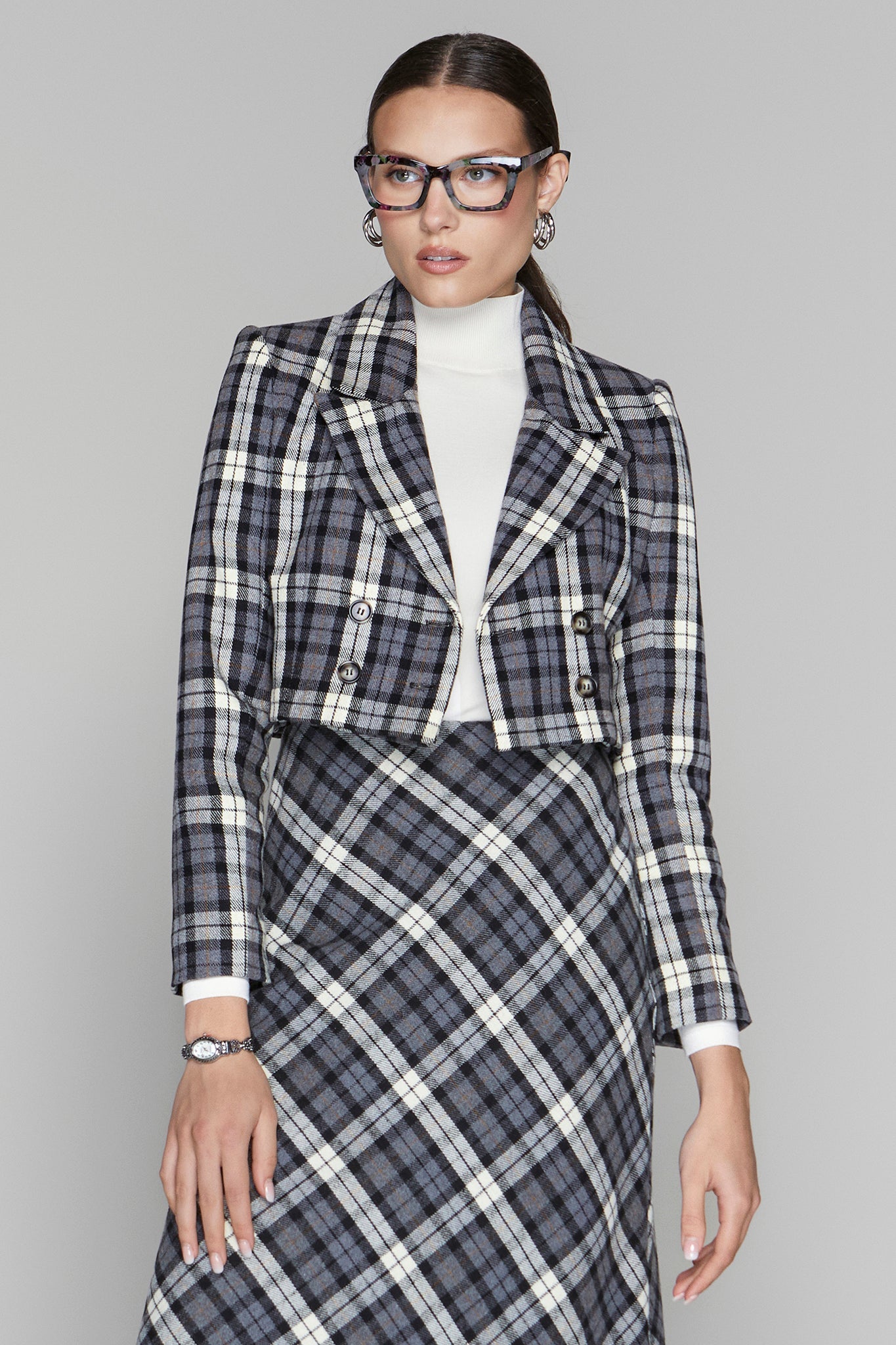 Woman wearing a plaid suit with a white shirt on a gray background