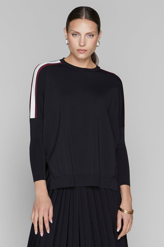 Woman wearing a black sweater with white and red stripes on a gray background