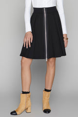 Person wearing a black skirt with a zipper, white shirt, and tan boots on a gray background