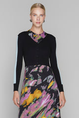 Woman wearing a black cardigan over a colorful dress with a gray background