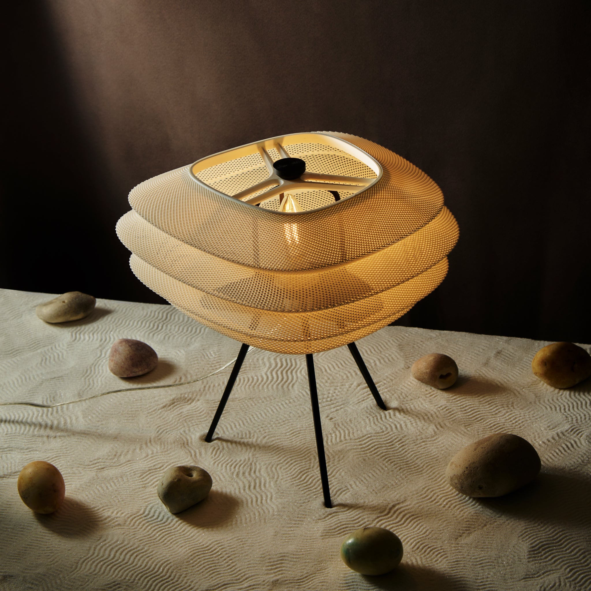 Modern table lamp with a mesh design on a textured surface with rocks