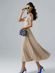 Woman in a beige pleated dress with colorful clutch and blue high heels on a gray background