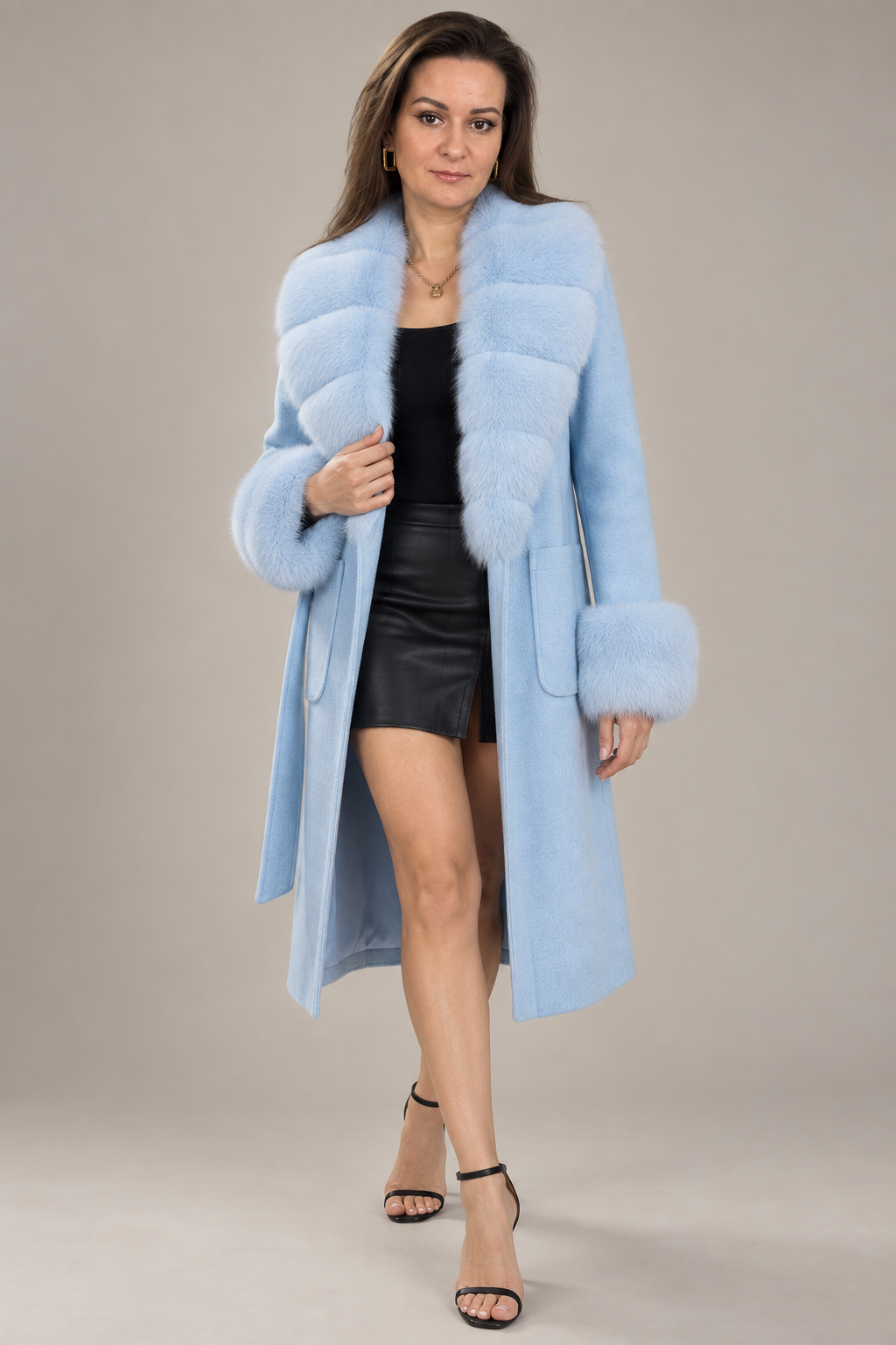 A woman modeling a light blue faux fur coat with a matching collar and cuffs, worn over a black top and black leather skirt, against a solid beige studio background.